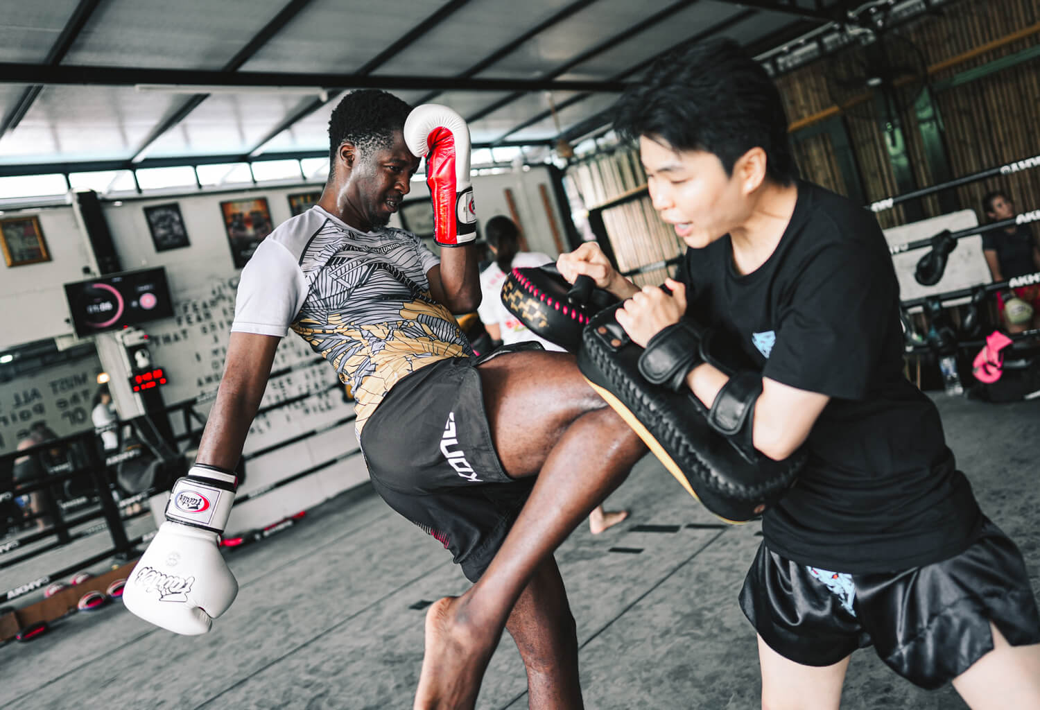 Student throwing a knee strike into a pad held by a Tiger Eye coach